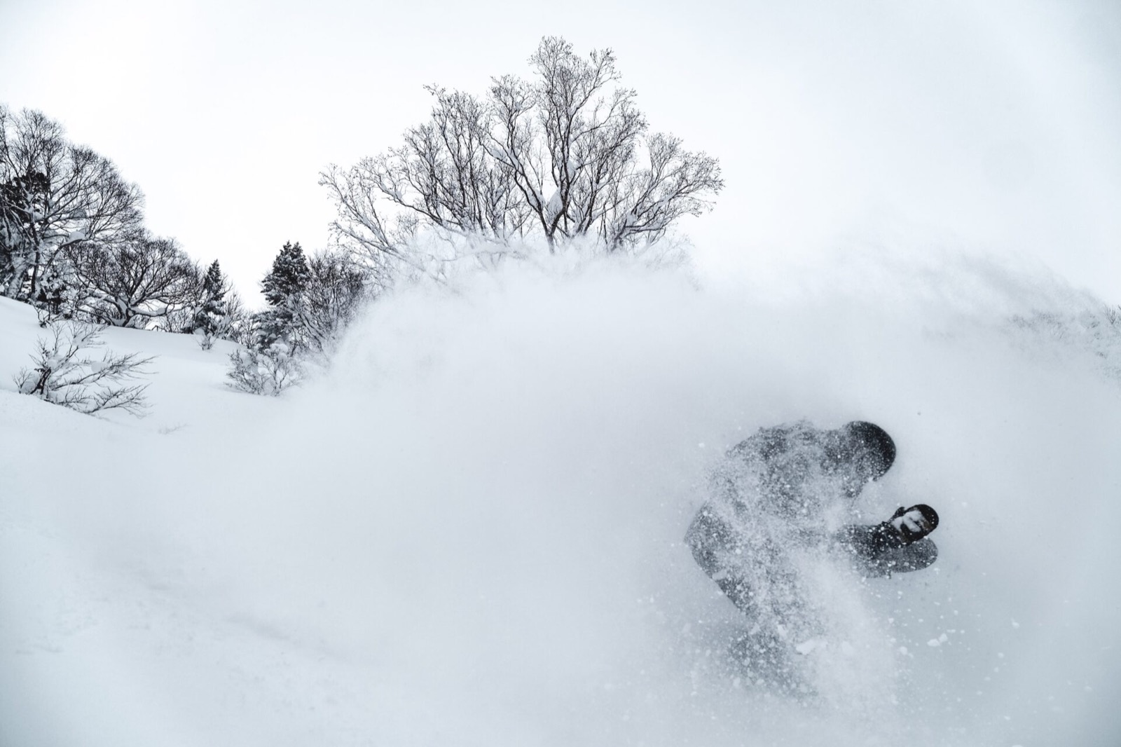 Snowboarder che apre una nuvola di powder in Honshu